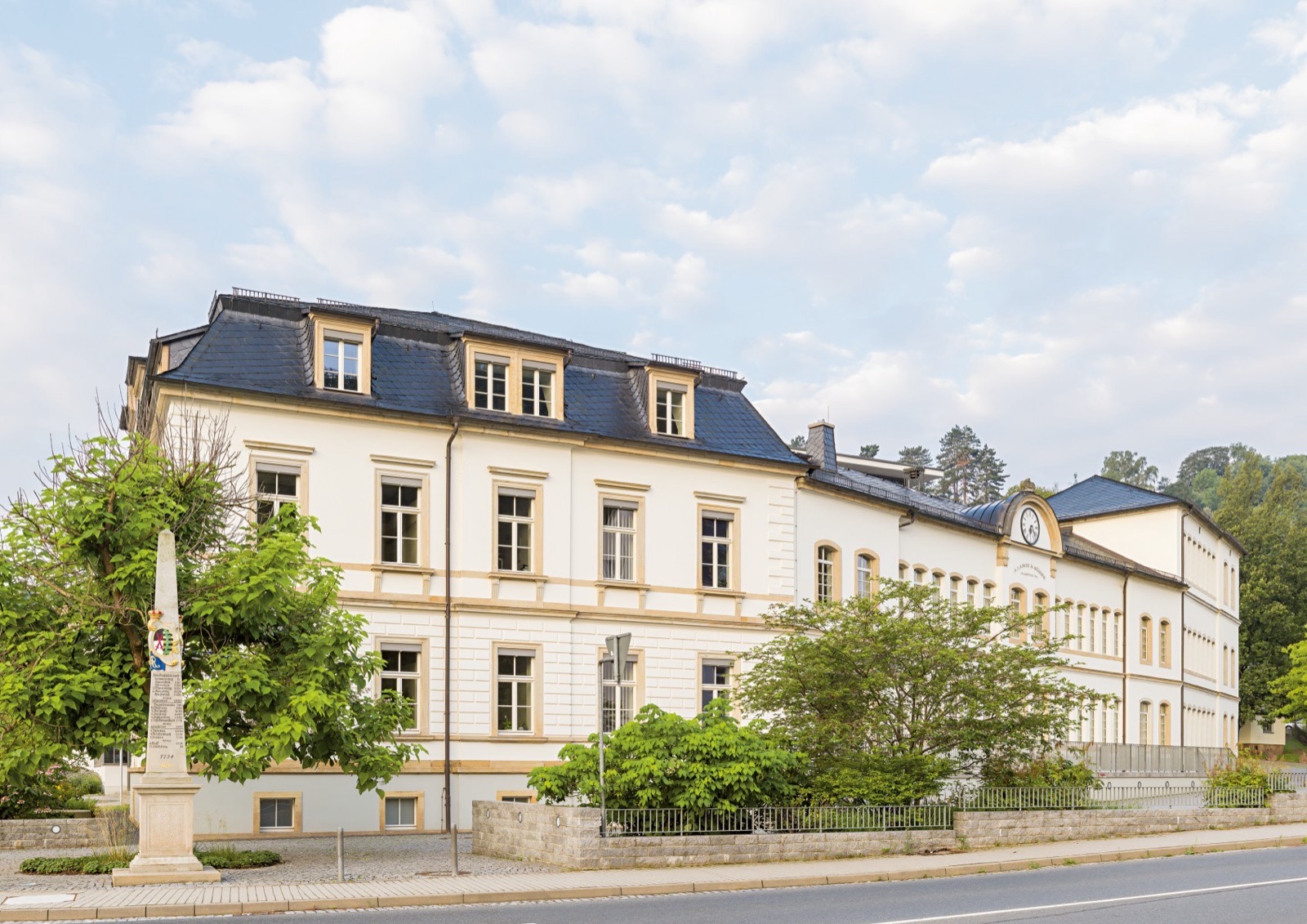 The A. Lange & Söhne Stammhaus in Glashütte, a restrained stone building against the wooded hills of the Ore Mountains in Saxony