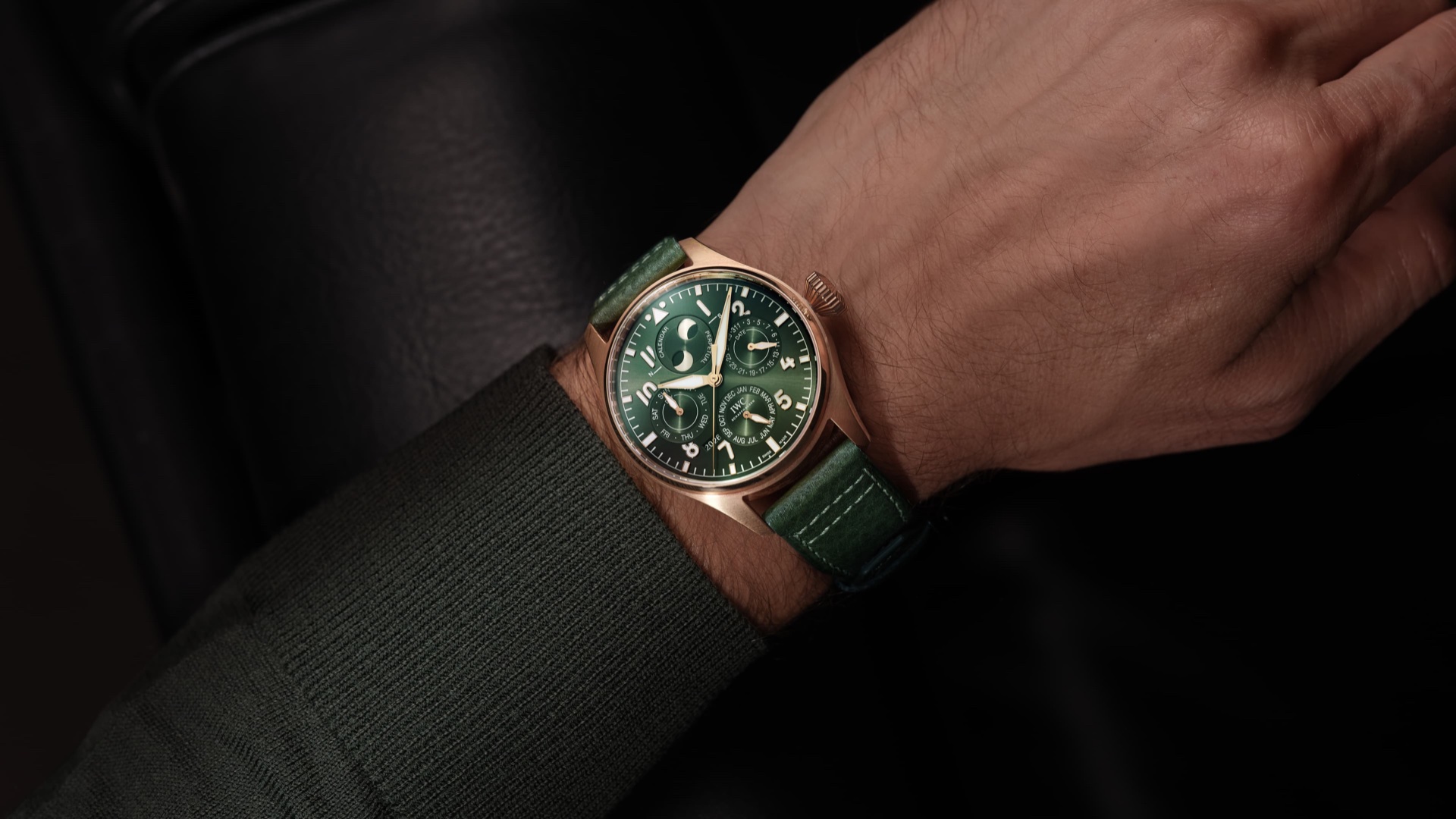 A Big Pilot's Watch on a wrist, its large black dial and prominent crown visible against a leather flight jacket cuff